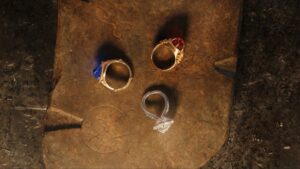 The Three Rings of Power made for the Elves in The Lord Of The Rings, arranged in a triangle on a brown stone slab, viewed from above.