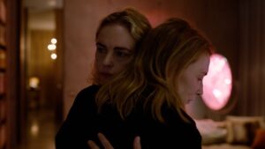 Nina Hoss as Sharon Goodnow and Cate Blanchett as Lydia Tar in TAR, hugging each other in a room with pink lighting.