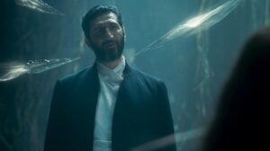 Fares Fares as Ishamael in The Wheel Of Time, wearing a loose black jacket over a white tunic. He has short dark hair, slicked-back, and a beard. His head is cocked to one side, and he is smirking, disregarding the razor-sharp blades of white light encircling him.