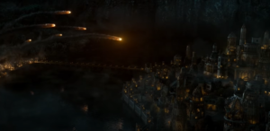 The city of Ost-in-Edhil in Eregion. It is night. Flaming missiles are being launched from catapults set up on side of a river at the walled city on the other side.