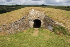 The Stoney Littleton Long Barrow, a low hill of turf with a stone wall built into it, in which there is a door leading into a tomb.