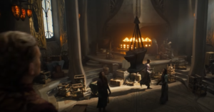 Charles Edwards as Celebrimbor, standing on a mezzanine above his forge, where Elves are hard at work, helping to lower an anvil into the center of the room.