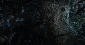 Close-up image of the Entwife, a humanoid tree with a large mouth and round eyes in its wooden face. It resembles a cherry tree, with white and pink blossoms.