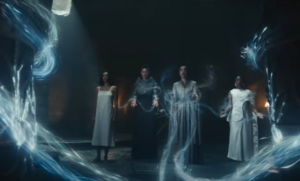 Madeleine Madden as Egwene al'Vere, Jennifer Cheon Garcia as Leane Sharif, Sophie Okonedo as Siuan Sanche and an unidentified fourth woman standing before the silver arches in the basement of the White Tower. Egwene has short dark hair and wears a white shift. Siuan has short dark hair and is wearing a silver coat and is channeling white ropes of the One Power with the assistance of Leane and the other woman, who wear blue and white, respectively.