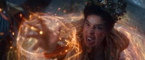 Sophie Okonedo as Siuan Sanche, throwing her arm out and channeling red and gold threads of the One Power into a spiral weave as she battles an unseen opponent. She has short dark hair under a lofty headdress made of gold lace and baubles, and wears a gilded coat.